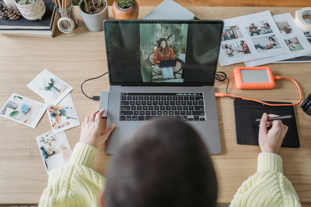 A person pictured from the back, sitting at a computer and doing some editing work